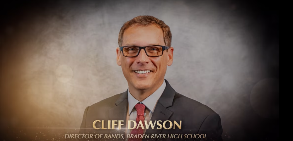 Man in a suit wearing glasses and smiling