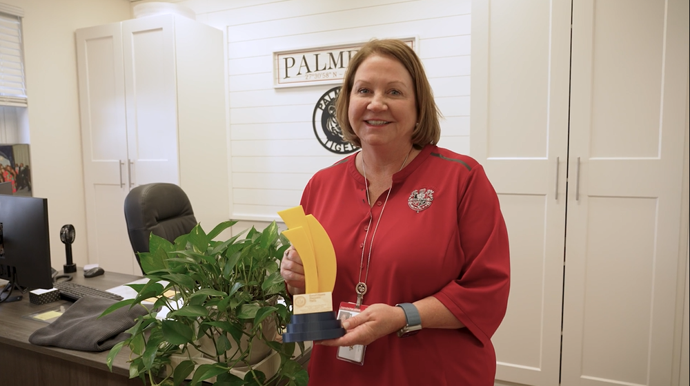 Principal holding a handmade award