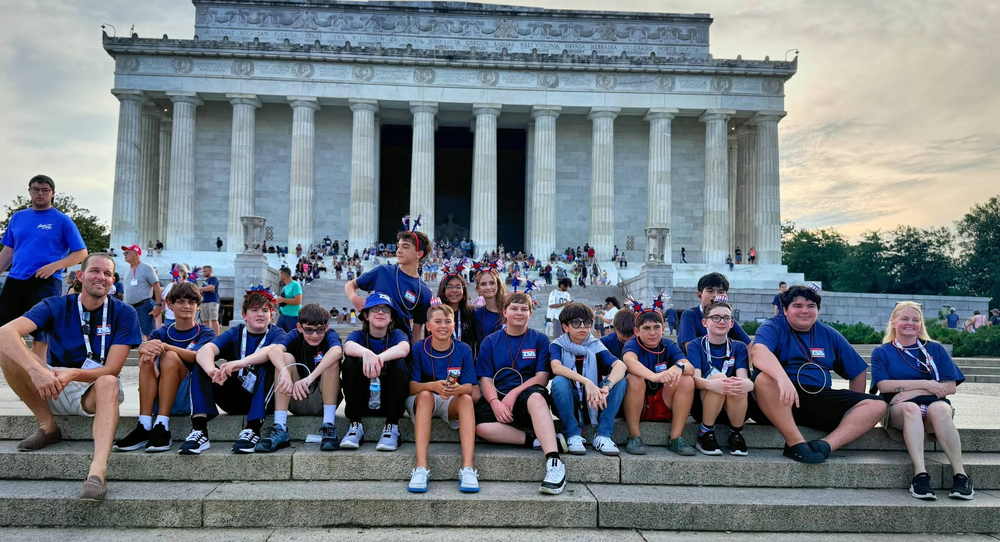 A middle school TSA (technology) organization sits on the steps of the National Mall in Washington, D.C.