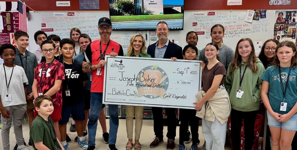 Students with teacher and a giant check made out to Joseph Baker for $500.
