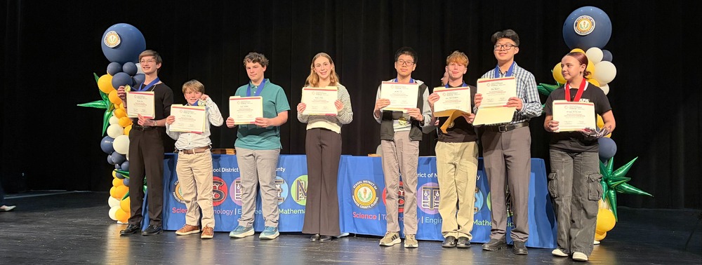 Students holding certificates of achievement on stage.