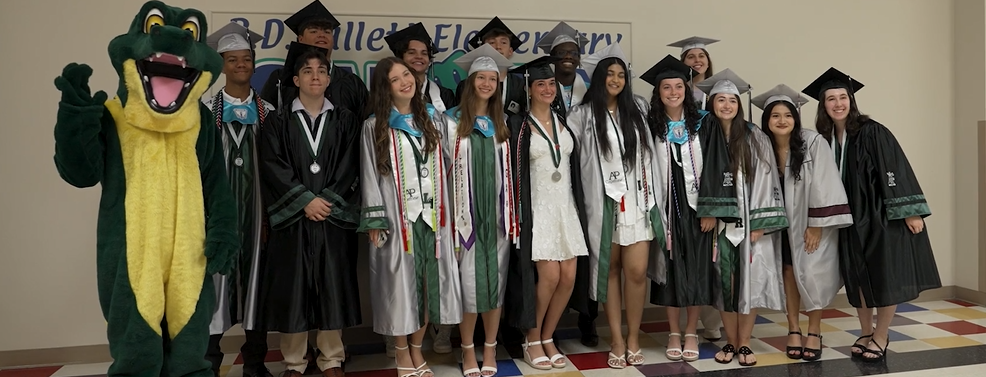 Graduates in their caps and gowns with standing next to a gator costumed mascot.