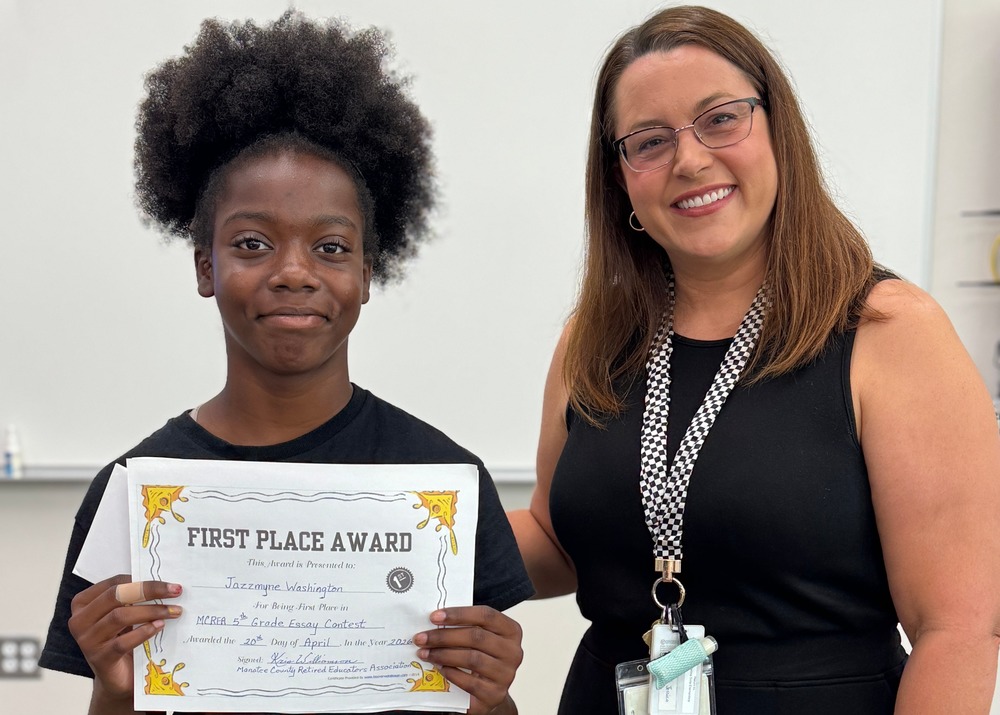 a young writer holds up a first place award for her essay.