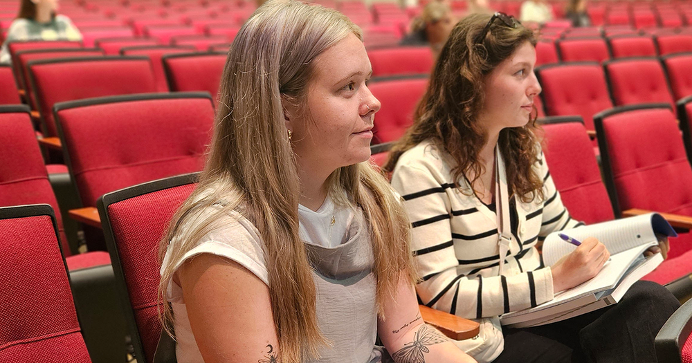 Two new teachers listen and take notes during an orientation session.