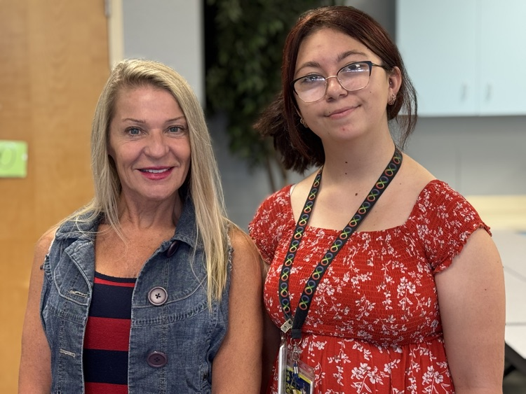 Two staff members smile while wearing red