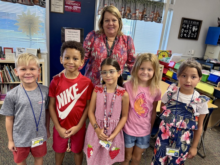 A class of student students, and their teacher wearing red