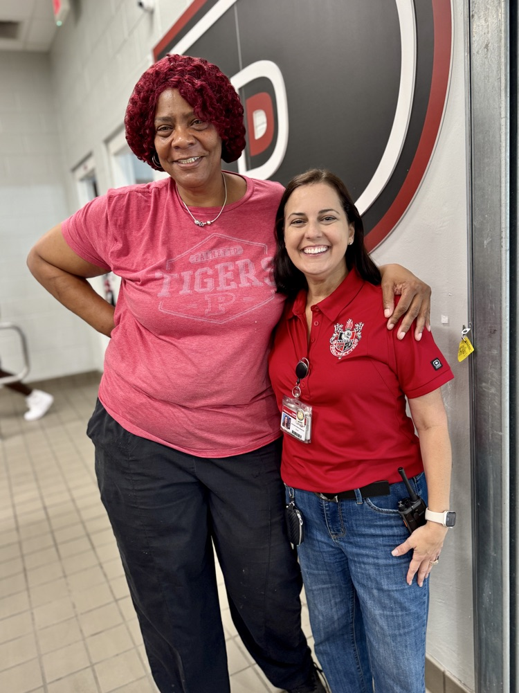 A food service worker, and school staff member smiling in the cafeteria