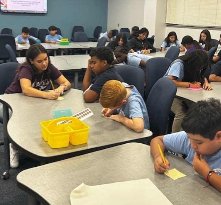 Elementary school students gathered around a large table discussing their assignment