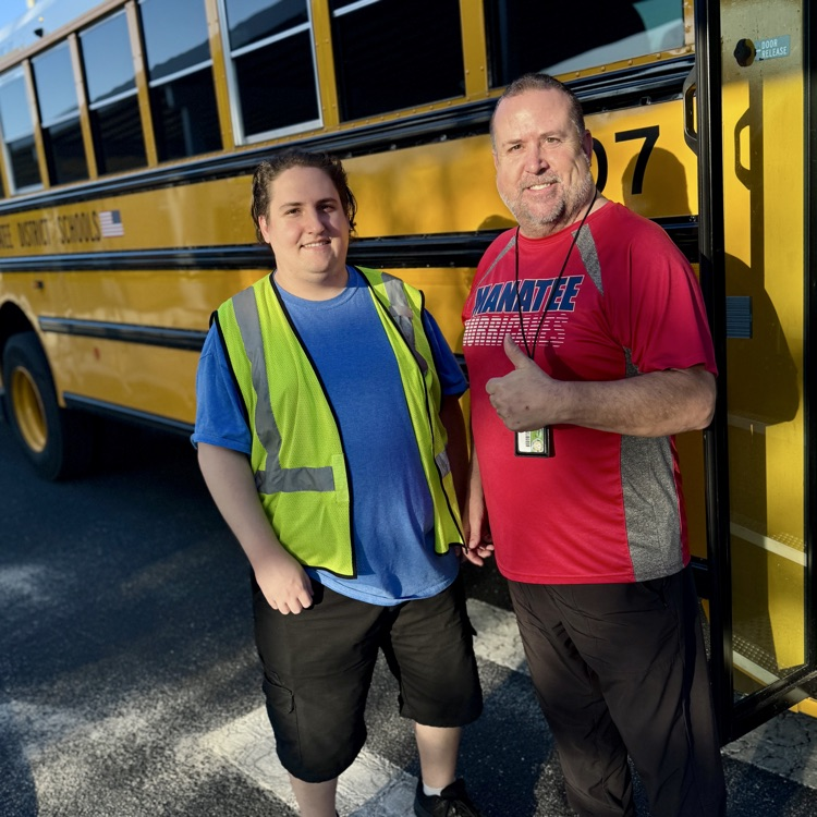 two men standing in front of a yellow school bus on a sunny day