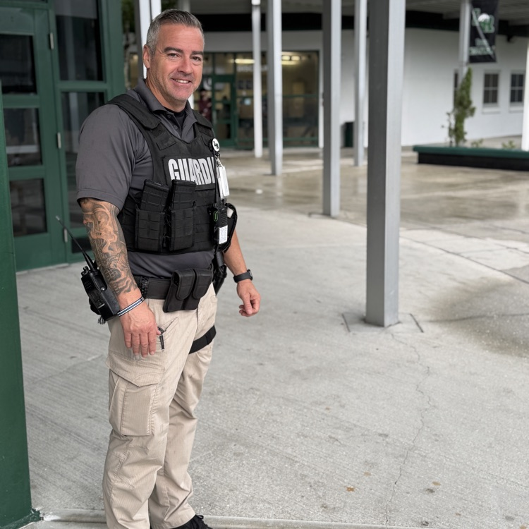 A school safety guardian smiles in the courtyard of a high school