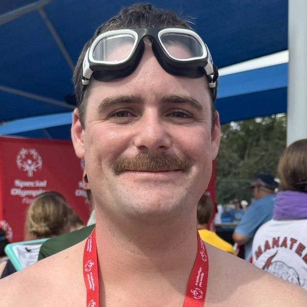 A swimmer with goggles on the top of his head and a red ribbon around his neck