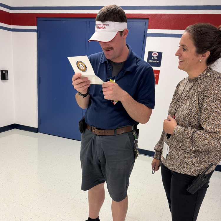 A man reading a congratulatory card while standing next to a woman, smiling