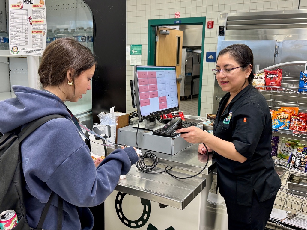 A food service employee scans a student ID in the cafeteria.