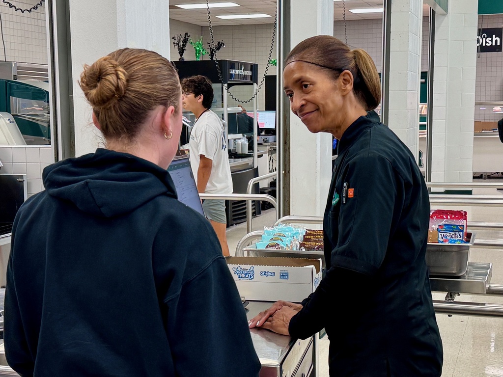 A food service employee smiles as she rings up a student lunch in the school cafeteria.