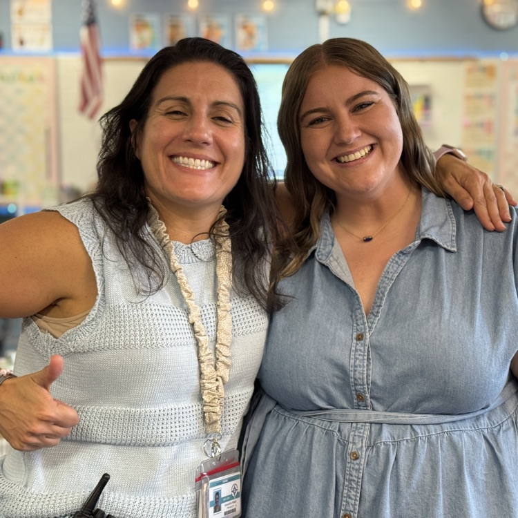 A school principal puts her arm around a fifth grade teacher