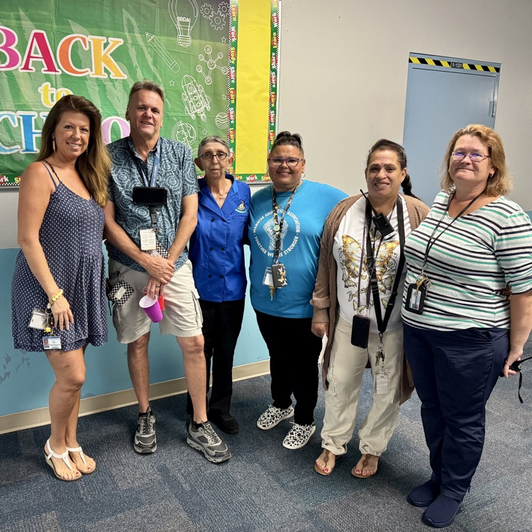 A group of long serving employees stand shoulder to shoulder at Samet elementary