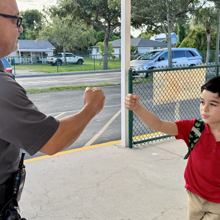 A school safety guardian, giving a student a fist bump at the beginning of the school day