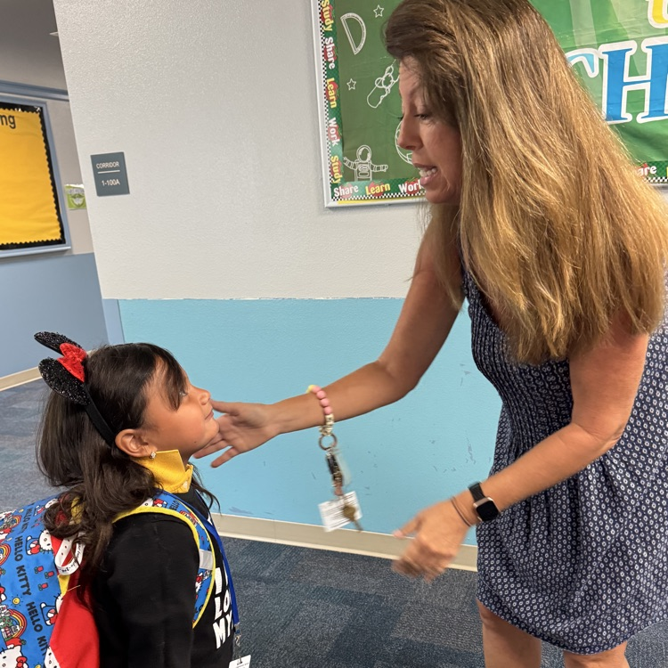A teacher speaking to a student in a school hallway