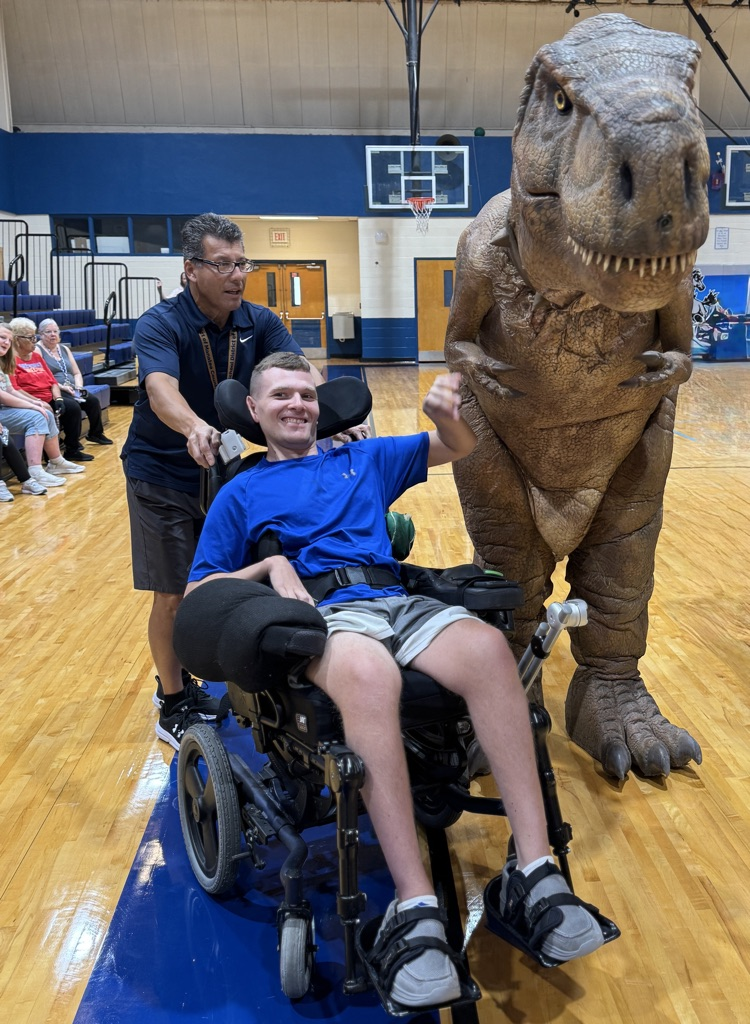 A student in a wheelchair next to an animatronic dinosaur