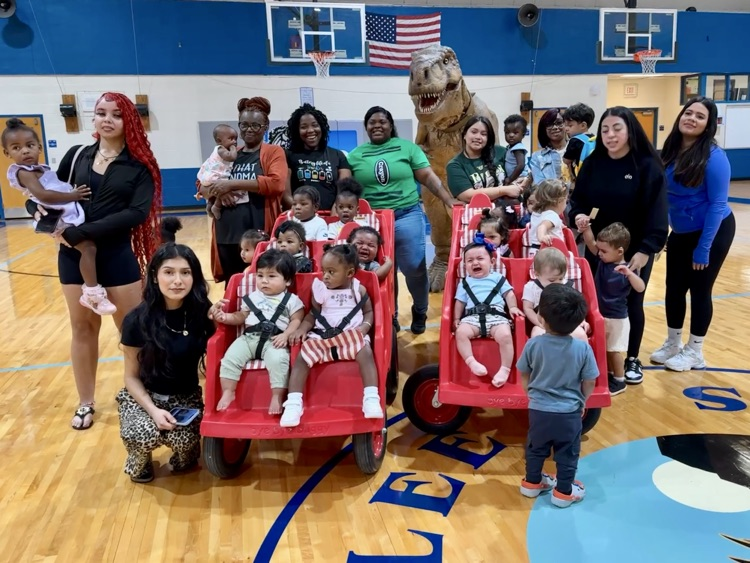 A group of teachers and kids gather in the gym of a school