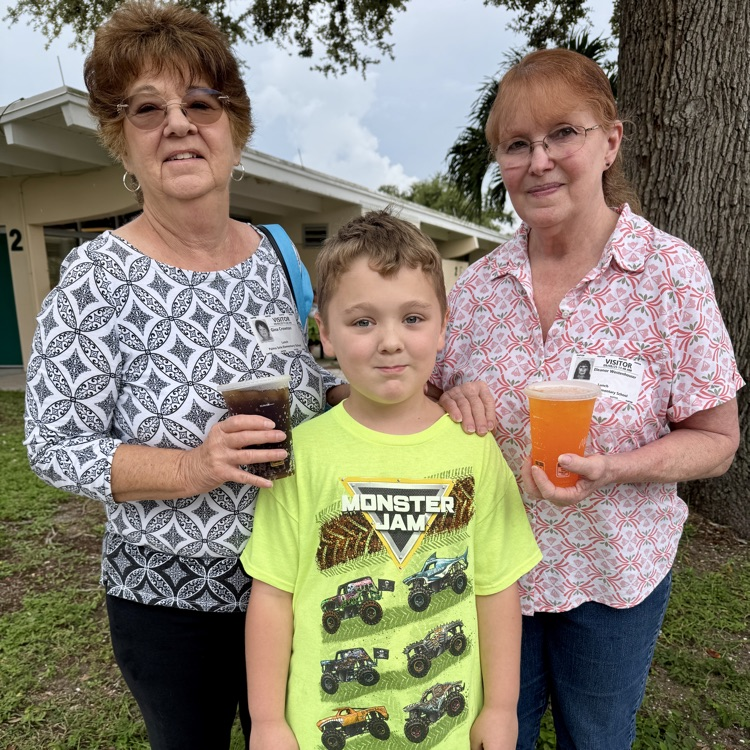 Two women smiling with a young boy at a school event. 