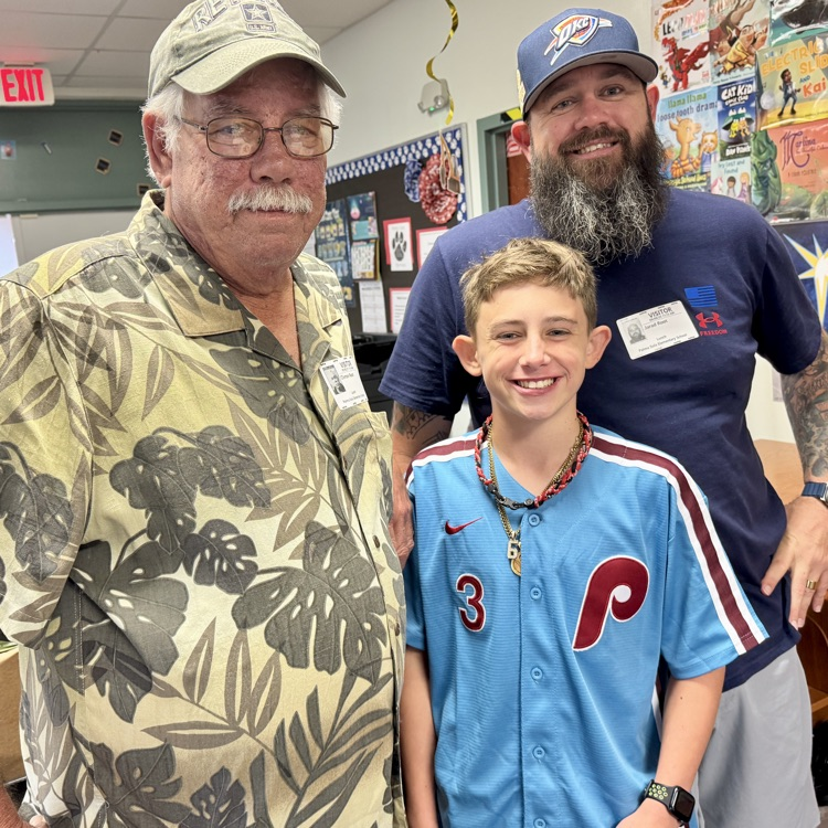 Three generations smile inside a school media center.