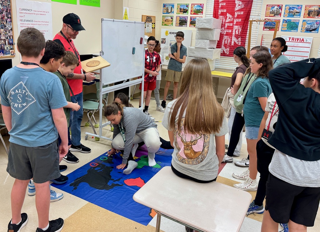 Students in a classroom watching their classmates play twister but using geography knowledge.