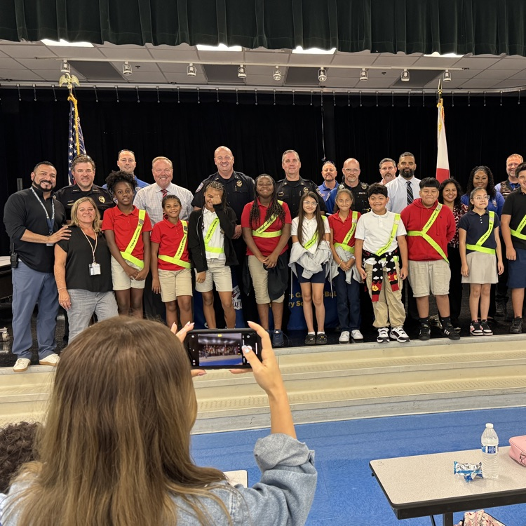 A teacher takes a photo on her cell phone of a group of students and police officers