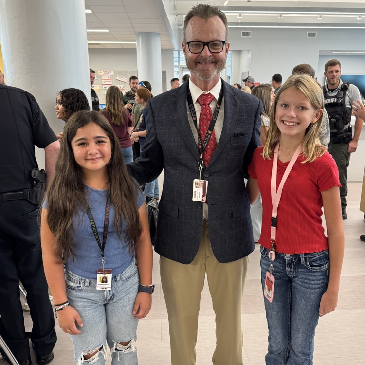 A teacher standing with two students in the media center
