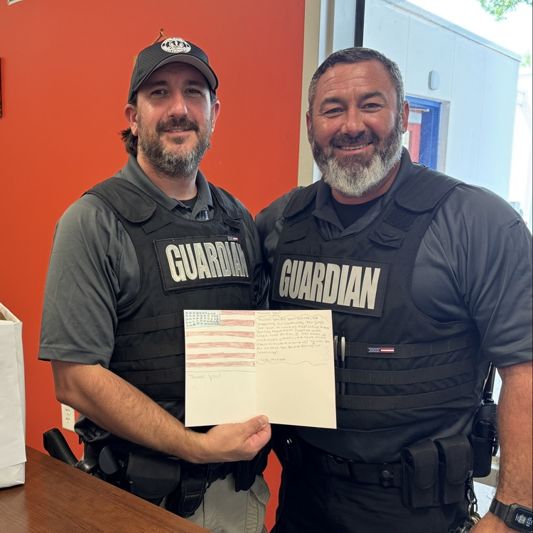 two school safety guardians hold up a handmade sign and appreciation for first responders