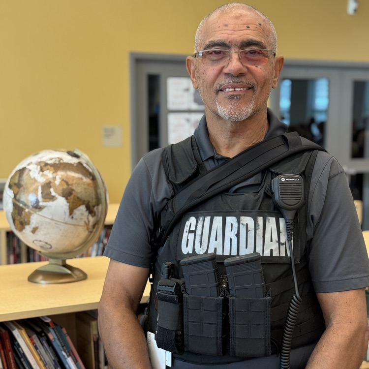 A school safety guard stands next to a globe in a school media center