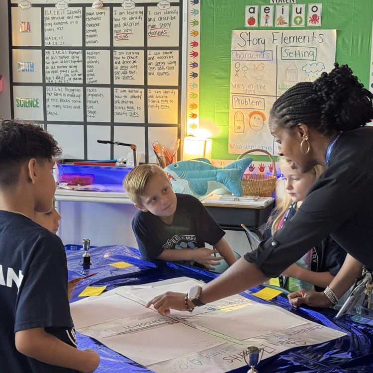 An educator points to an assignment as students watch on. 