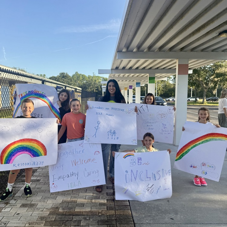 A group of student leaders holding signs with words of encouragement during start with hello week