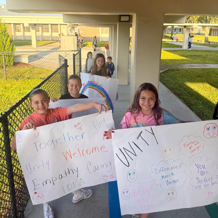 Students gathered while holding posters with encouraging words, such as hello and friendship