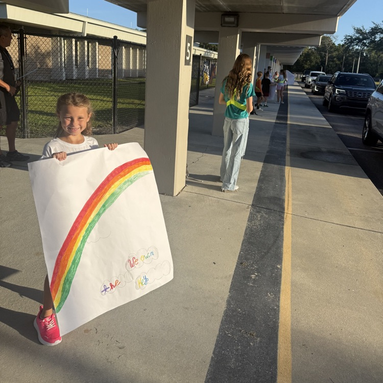 A student holding a sign that says hello to greet fellow students