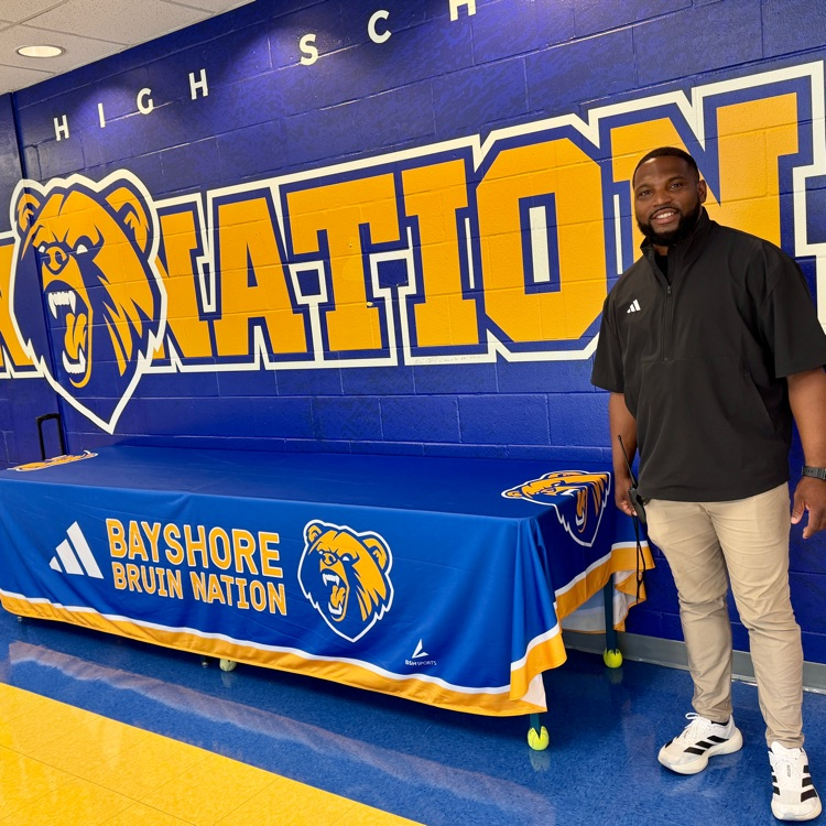 standing next to a high school logo and blue and yellow color scheme