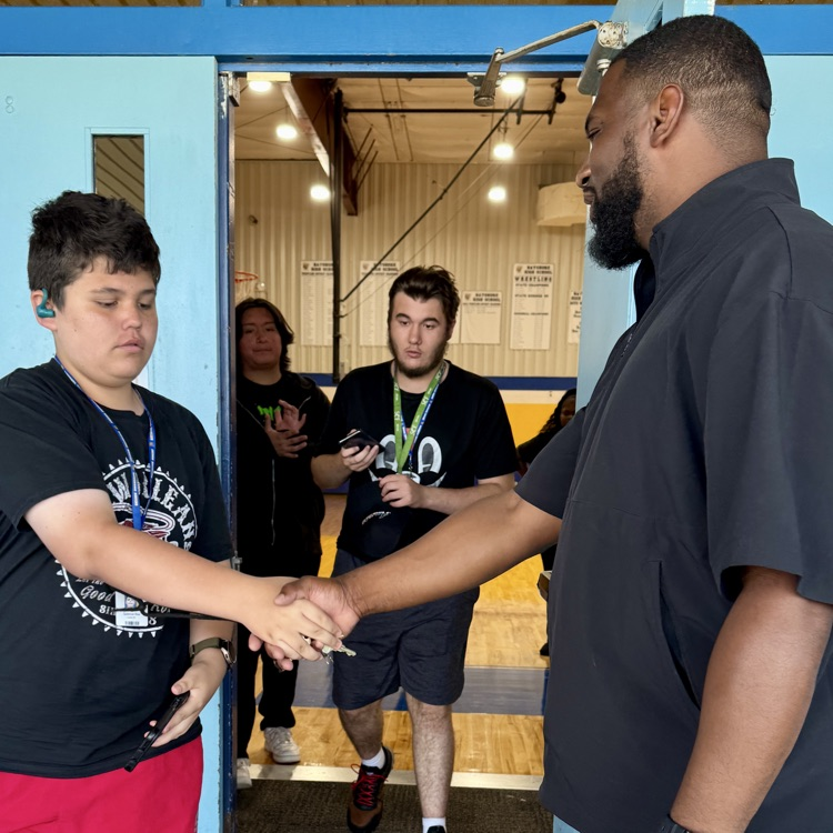 A student greets the school athletic director with a handshake
