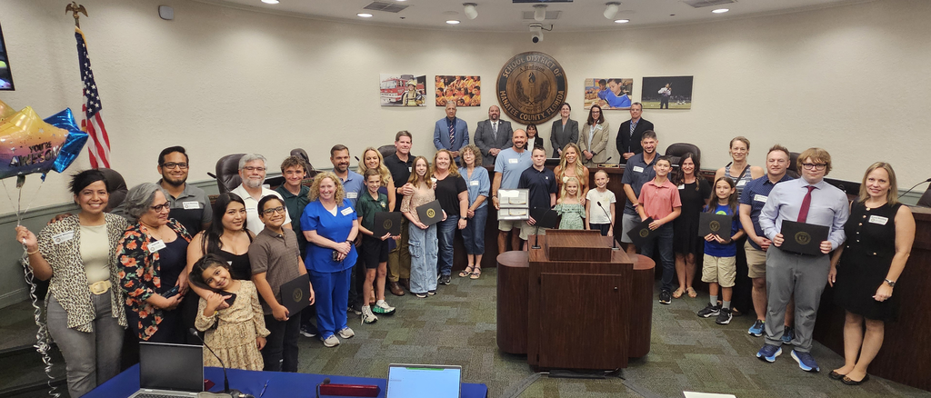 Students and families smile for a photo at a school board meeting during a recognition.