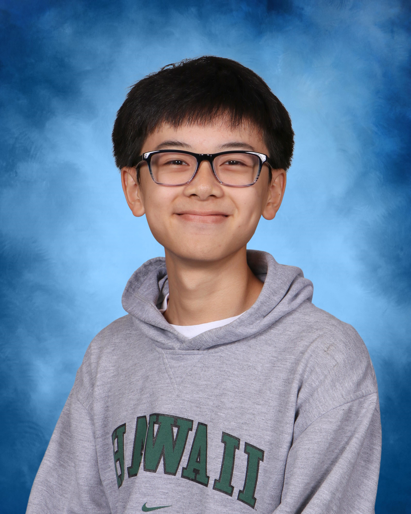 A smiling student who is wearing glasses and a grey sweatshirt.