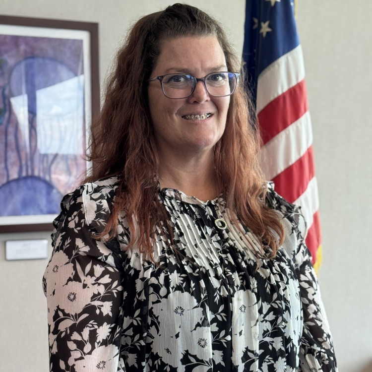 A woman smiling in front of an American flag.