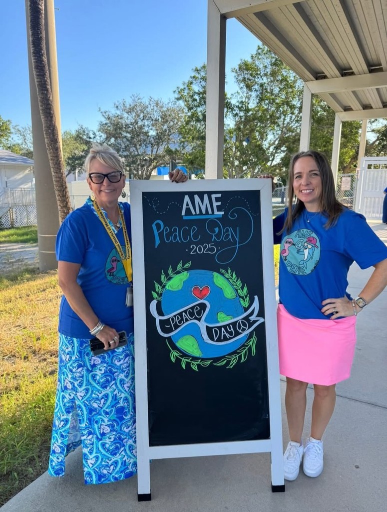 Principal and Literacy Coach standing on either side of a sign that reads "AME Peace Day 2025"