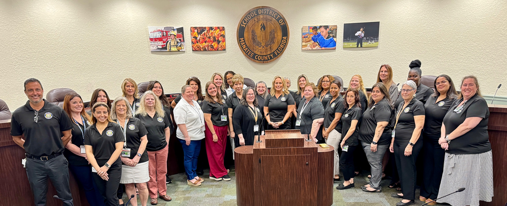 HR employees gather and smile in the school board room.