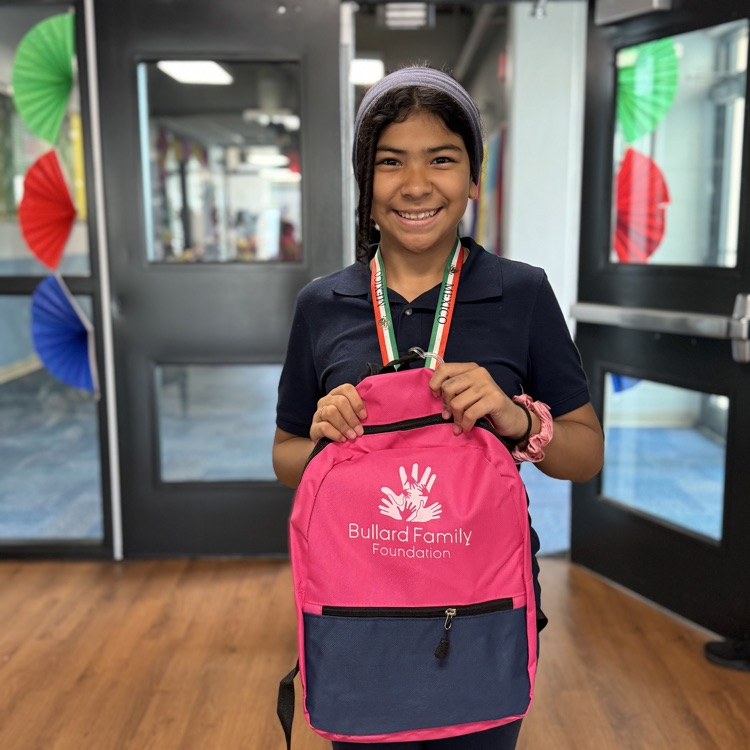 A little girl with a huge smile, holding a pink backpack