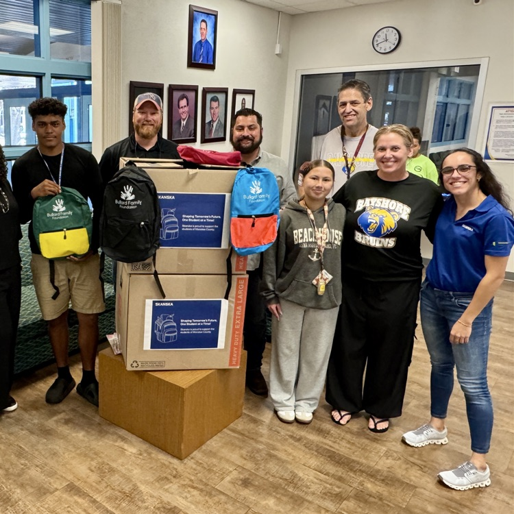 adults and kids smiling with their backpack donation