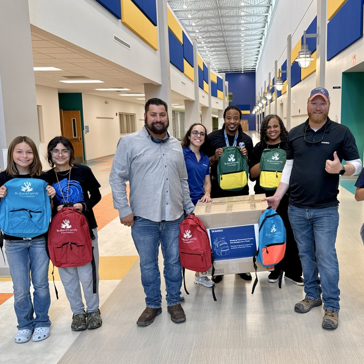 adults and kids smiling in the center of a middle school