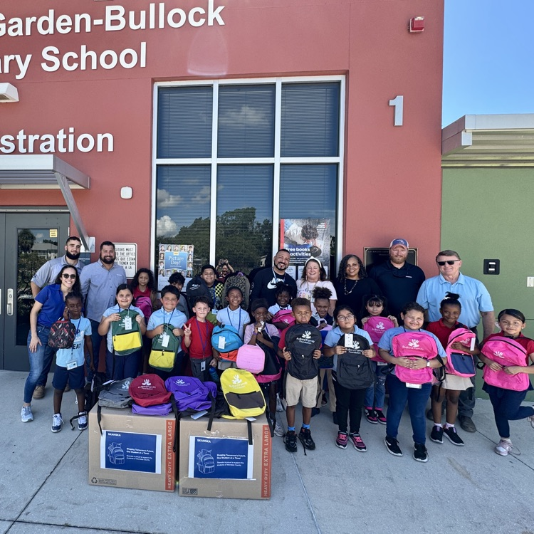 kids holding their new backpacks which were donated by a construction company