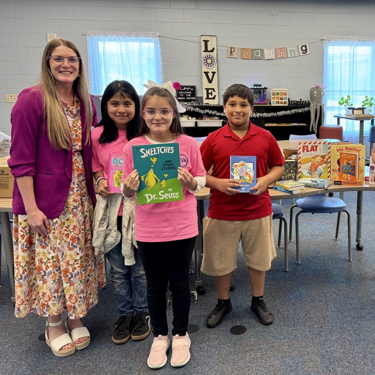 an assistant principal with a few smiling kids grateful to have new books for their media center