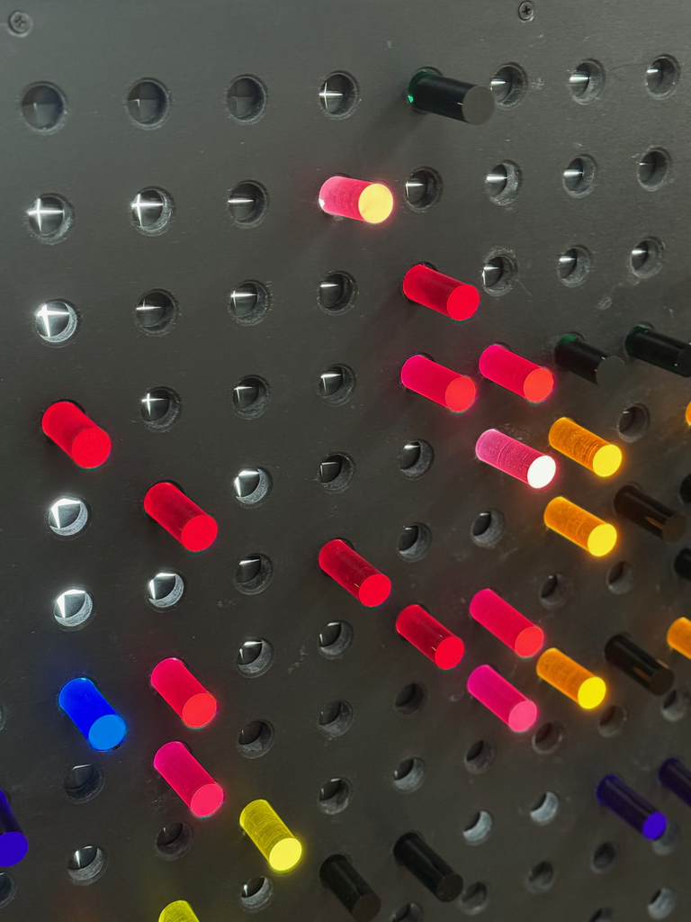 Colorful plastic pegs light up in a black background.