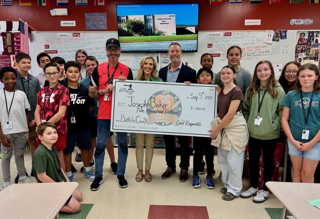 A teacher receiving a check for $500 surrounded by students.