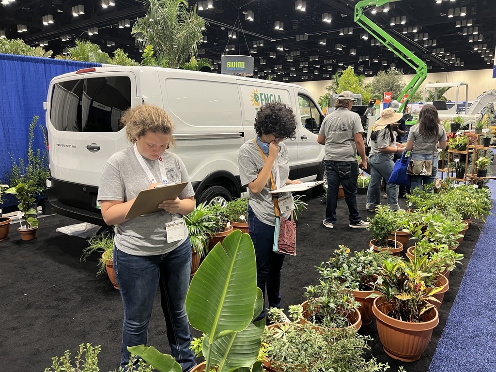 FFA students examining plants and writing on clipboards. 